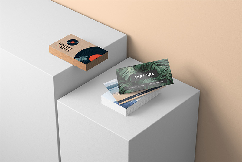 Professionelle Visitenkarten auf weißen Podesten mit naturbezogenen Logos.