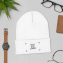 Lifestyle-Muster einer bestickten und individuell gestalteten Wintermütze, flach liegend, umgeben von einer Uhr und einer Brieftasche
