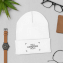 Amostra estilo de vida – chapéu de inverno bordado personalizado apoiado em superfície e rodeado por um relógio e uma carteira