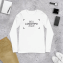 Camiseta manga longa colocada em um fundo rodeado por itens como telefone e carteira